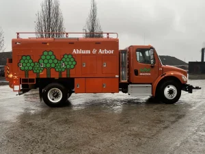Orange Ahlum & Arbor chip truck body with storage compartments parked outdoors.